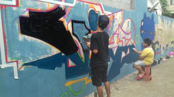 
					Seniman Mural saat melukis di dinding permukiman di kawasan Pondokcina. (FOTO : Aji Hendro/Harian Sederhana)