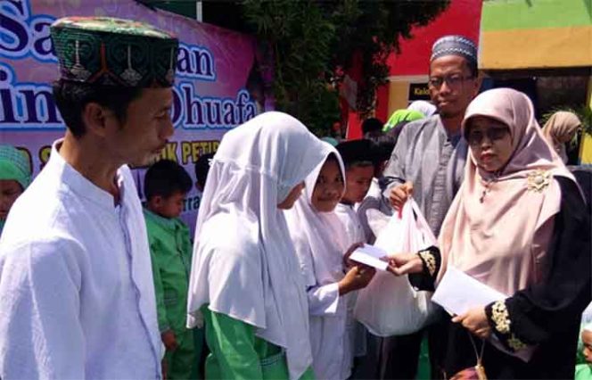 
					Kepala SDN Pondok Petir 01, Euis Nurhayati secara simbolis menyerahkan bingkisan berupa bahan makanan dan uang kepada siswa yatim di lingkungan sekolahnya.  