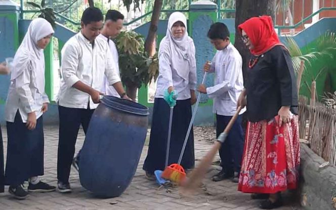 
					Kompak, siswa dan wali kelas SMPN 11 Bekasi bersih-bersih lingkungan sekolah.