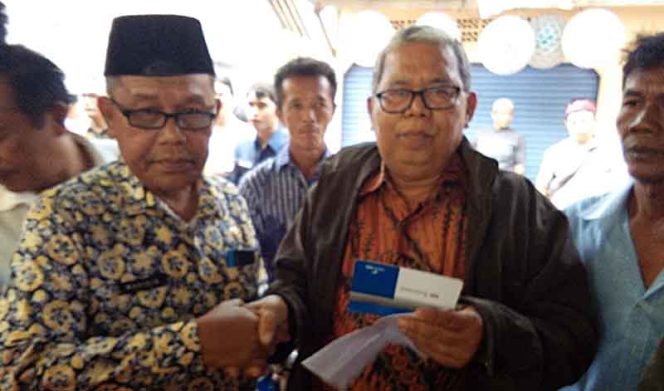 
					Lurah Kedaung, Wahidin (kiri) secara simbolis menyerahkan rekening bank untuk bantuan RTLH.