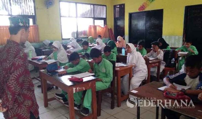 
					Sodikun, guru kelas VI sedang memperhatikan siswa mengikuti PAS di hari terakhir.