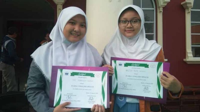 
					Dua siswi SMA dan SMK Genesis Medicare menunjukkan sertifikat juara lomba pidato bahasa inggris.