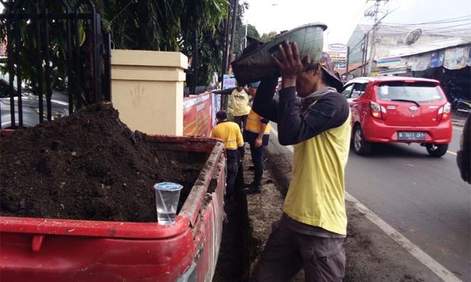 
					Satgas PUPR mengangkut lumpur dari saluran air di depan kantor Kecamatan Sawangan.