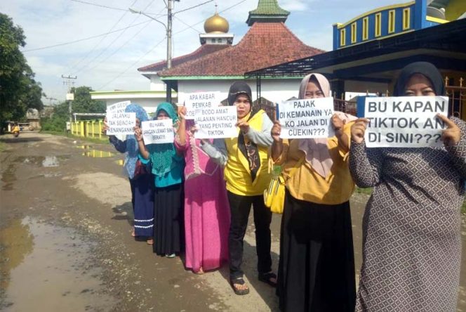 
					Emak-emak yang sengaja menyindir kinerja Bupati Cellica melalui selembar kertas.