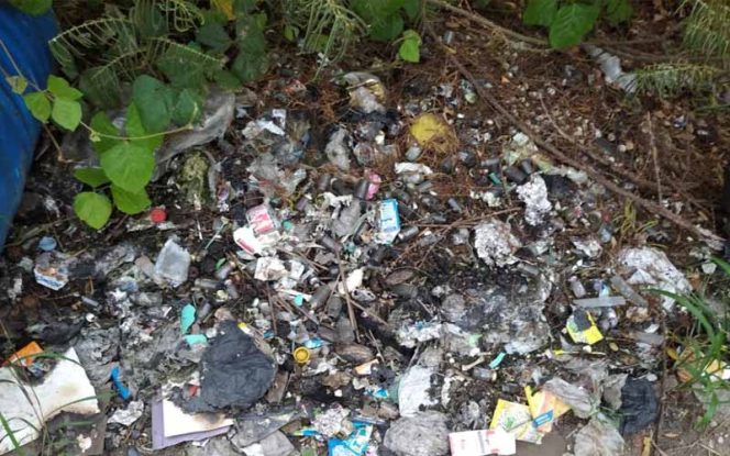 
					Terlihat sejumlah barang limbah B3 terdiri dari ampul obat, serta bekas suntikan, kapas dan lain-lain dibuang begitu saja di sebuah lahan kosong.