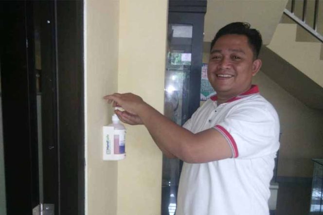 
					Akbar staf sukarelawan sedang menggunkan hand sanitizer.