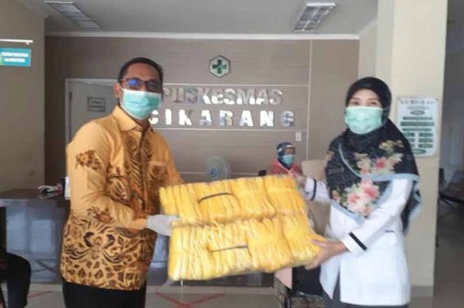 
					Ketua Fraksi Golkar DPRD Kabupaten Bekasi, Asep Surya Atmaja (kiri) bagikan 1000 masker di setiap puskesmas.