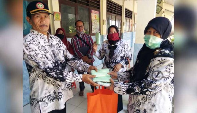 
					Euis Nurhayai (Kanan) Ketua Kwartir Pramuka Kecamatan Bojongsari menyerahkan saat menyerahkan bantuan masker ke pengurus PGRI.
